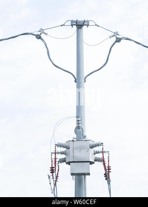 Moderne drei Phase-Verteilertrafos auf einer hohen Spannung elektrische Pole. Weißen Himmel Hintergrund Stockfoto