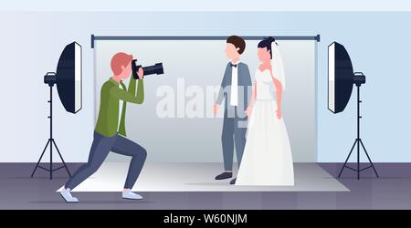 Professionelle Hochzeit Fotograf Aufnahmen auf der Kamera frischvermählte Paar braut und Bräutigam die in modernen Fotostudio Interieur voller Länge posing Stock Vektor