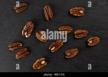 Menge ganze Frische braune Pekannuss Hälfte flatlay am grauen Stein Stockfoto