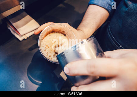 Nahaufnahme des Barista Hände so kalt Eiskaffee cappuccino Latte. Kellner server gießen Drink in durchsichtigen Schale. Kleine Unternehmen und Person ein Stockfoto