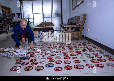 Chinesische älterer Mann Huang Junde zeigt Abzeichen des Porträts von verstorbenen Vorsitzenden Mao Zedong, die er in den vergangenen 50 Jahren in seinem Haus in Chong gesammelt Stockfoto