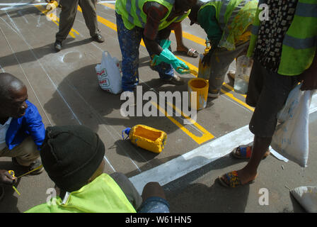 Die Beschäftigten im Straßenverkehr Malerarbeiten Zebrastreifen Streifen auf der Fahrbahn, Lilongwe, Malawi, Afrika. Stockfoto