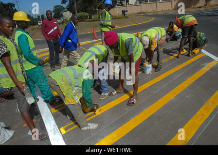 Die Beschäftigten im Straßenverkehr Malerarbeiten Zebrastreifen Streifen auf der Fahrbahn, Lilongwe, Malawi, Afrika. Stockfoto