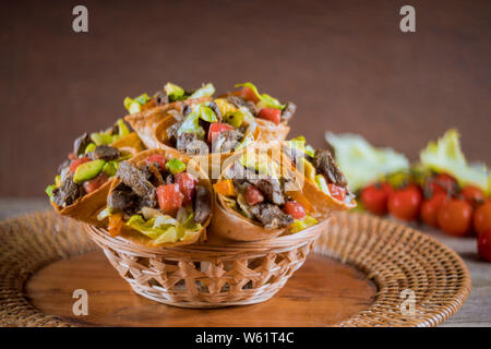 Gesunde Vorspeisen Rindfleisch Salat in der Tortilla Kegel in Korb Stockfoto