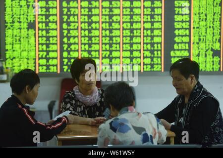 Betroffenen chinesischen Investoren Blick auf einen Bildschirm, der die Preise der Aktien (rot für Preis steigt und grün für den Preis fallen) auf einer Börse brokerage House Stockfoto