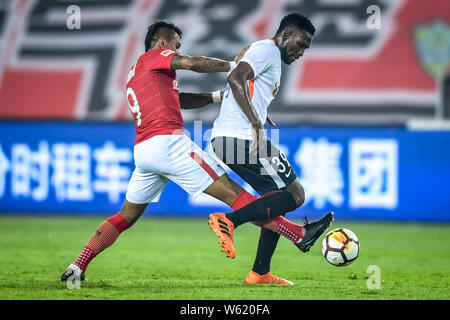 Brasilianische Fußballspieler Paulinho, links, von Guangzhou Evergrande Taobao Herausforderungen senegalesischer Fußballspieler Makhete Diop von Peking Renhe in Ihrer Stockfoto