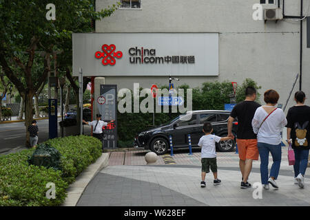 ---- Fußgänger vorbei an einem Namensschild von China Unicom (China United Telecommunications Corp) in Shanghai, China, 28. August 2018. Stockfoto