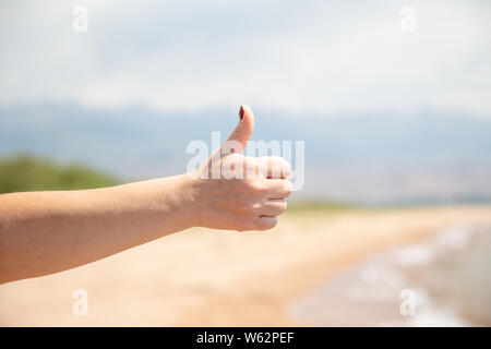 Die teenage Hand zeigt eine Klasse. Vor dem Hintergrund der Natur und Wasser. Stockfoto