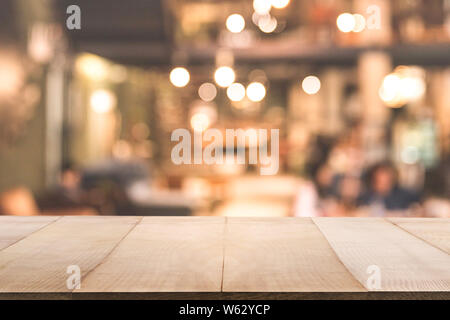 Leere Holztisch vor unscharfen Hintergrund des Café oder Restaurant Interior abstrakt. Für Mock up Template für die Anzeige von Ihrem Design o Stockfoto