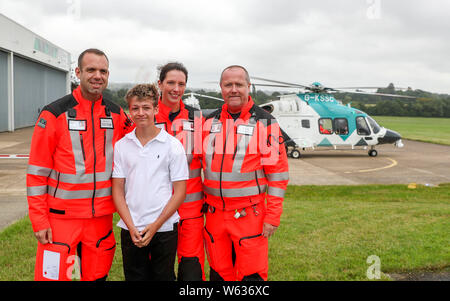 Joe Pelham, 14, erfüllt die Teammitglieder Arzt Richard Lyon und Sanitäter Sam Taylor und David Wright von der Air Ambulance Kent Sussex Surrey, der sein Leben an ihrer Basis in Redhill, Surrey gespeichert. Joe wurde von der Mannschaft behandelt, nachdem er durch ein Auto während Radfahren getroffen worden war. Stockfoto