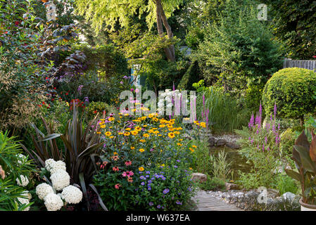 Gemischte Blume Grenze mit Gartenteich, in einem englischen Vorort Garten. Stockfoto