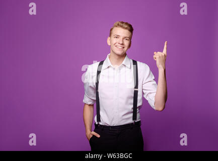 Junge lustig smilling Mann auf lila Hintergrund im klassischen Stil, haben eine Idee Stockfoto