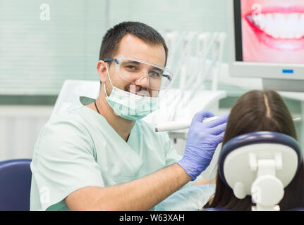 Junge Frau im Zahnarztstuhl mit geöffnetem Mund Zahnarzt sitzen während der Prüfung. Stockfoto