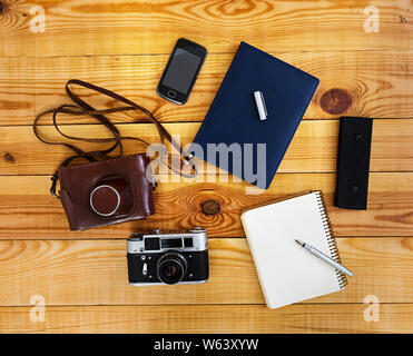 Flach, Ansicht von oben Bürotisch Schreibtisch. Schreibtisch Arbeitsbereich mit retro Kamera, Tagebuch, Stift, Fall auf Holz- Hintergrund. Stockfoto