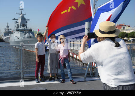 Chinesische Kinder holding Flags von China auf die Geführte-missile destroyer Xi'an der chinesischen Volksbefreiungsarmee Marine Oberfläche tritt am Ufer der Leutnant Schmidt in Sankt-Petersburg, Russland während der Vorbereitungen für die Russische Marine Parade Stockfoto