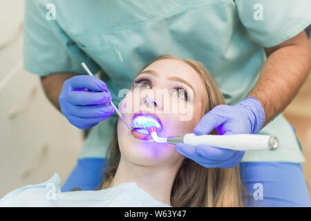 Zahnarzt tun Verfahren mit zahnmedizinischen Härtung mit UV-Licht in der Klinik Stockfoto