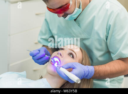 Zahnarzt tun Verfahren mit zahnmedizinischen Härtung mit UV-Licht in der Klinik Stockfoto