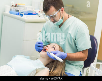 Zahnarzt tun Verfahren mit zahnmedizinischen Härtung mit UV-Licht in der Klinik Stockfoto