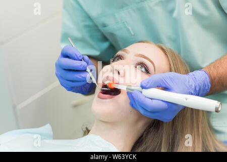 Zahnarzt tun Verfahren mit zahnmedizinischen Härtung mit UV-Licht in der Klinik Stockfoto