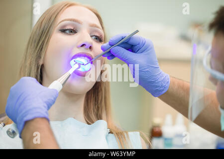 Zahnarzt tun Verfahren mit zahnmedizinischen Härtung mit UV-Licht in der Klinik Stockfoto