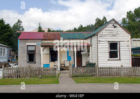 Queenstown, Tasmanien: April, 2019: Typische freistehende Doppel fronted bungalow Haus mit einem Wellblechdach, weißen Lattenzaun und Veranda in Queenstown. Stockfoto