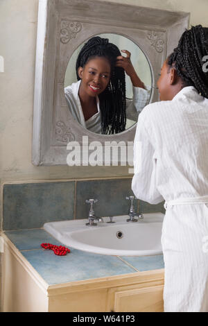 Hübsche junge afrikanische amerikanische Frau, die Ihre morgendliche Routine zu tun vor dem Badezimmerspiegel Stockfoto