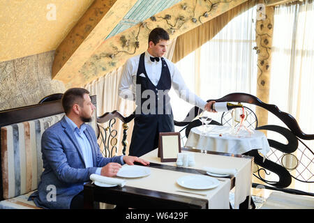 Der Sommelier gießt den Wein in der Karaffe in der Nähe der Gast im Restaurant Stockfoto