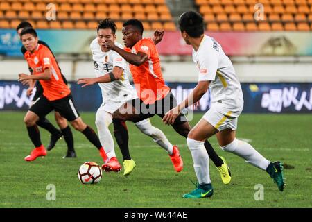 Kenianische Fußballspieler Ayub Masika, Mitte, von Peking Renhe passt den Ball gegen Spieler von Guizhou Hengfeng in der 21. Runde während der Stockfoto