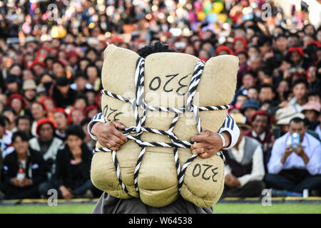 Ein Teilnehmer versucht, ein sandsack während eines starken Mannes Herausforderung in Markam County, Chamdo Stadt, im Südwesten Chinas Tibet autonomen Region, 4 Septem zu heben Stockfoto