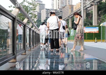 Besucher Spaziergang entlang eines Skywalk 20 Meter über dem Boden, wie sie sich vorbereiten, zu beobachten, eine Einschienenbahn verbindet den Bahnhof von Chongqing der Light Rail Linie 2 durch eine Re Stockfoto