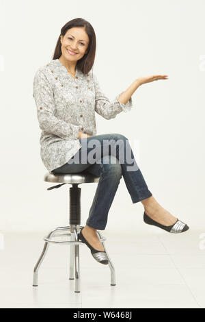 Frau sitzt auf einem Hocker mit ihrem Arm ausgestreckt Stockfoto