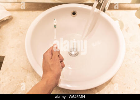 Ein Mann hand mit Zahnbürste und Zahnpasta auf der Spüle im modernen Bad. Stockfoto