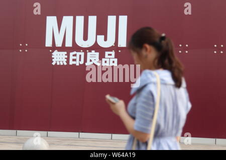 ---- Einen Fußgänger an einer Werbung für Muji in Jiangbei district, Chongqing, China, 28. Juli 2018. Eine Filiale der japanischen retai Stockfoto