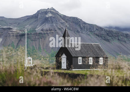 Das berühmte Schwarze Kirche von Budir auf Snaefellsnes Halbinsel Region in Island. Erstaunlichen Felsen und Blick auf die Berge im Hintergrund. Stockfoto