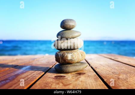 Die Steine der Pyramide auf über Strand holzdeck als Symbol für Harmonie, Zen und Balance Stockfoto