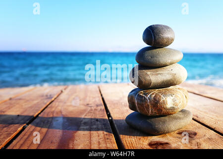 Die Steine der Pyramide auf über Strand holzdeck als Symbol für Harmonie, Zen und Balance Stockfoto