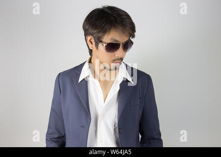 Porträt Mann im blauen Anzug tragen schwarze Brillen oder Brillen. Porträt Mann im blauen Anzug und weißes Hemd auf grauem Hintergrund in Smart Style Stockfoto