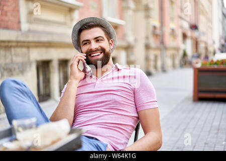 Entspannt man am Telefon zu sprechen im Außenbereich Cafe sitzen in der Stadt Stockfoto
