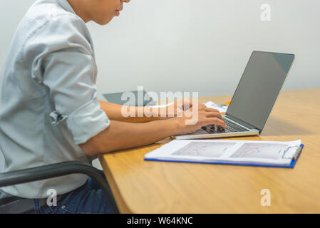 Junge asiatische Büro Mann bei der Arbeit am Laptop Stockfoto
