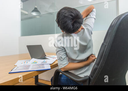 Restless Geschäftsmann seinen Rücken und Nacken dehnen im Büro Stockfoto