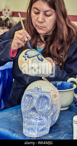 Mexiko- Stadt, Puebla Stadt, fokussierte reife Frau Malerei Keramik Totenschädel in der uriarte Haus, Mexiko. Stockfoto