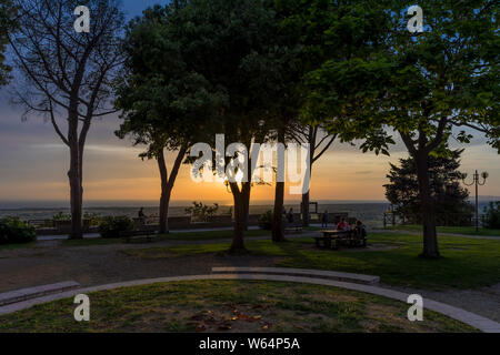 Die Leute bewundern Sie den Sonnenuntergang von einer Terrasse mit Panoramablick in das mittelalterliche Dorf Castagneto Carducci, Toskana, Italien Stockfoto