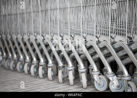 Shopping Carts geordnet in einer Reihe auf der Straße in der Nähe des Supermarktes. Close up Rad der Warenkorb. Konzept der Shopping. Selektive konzentrieren. Stockfoto