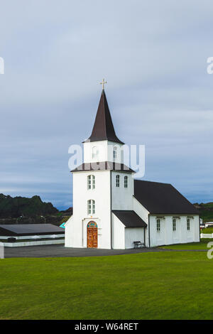 Kirche mit schwarzem Dach, weißen Wänden in traditionellen nordischen minimalistischen Stil auf Vestmannaeyjar Insel Heimaey in Island. Einfache Architektur, Grün Stockfoto