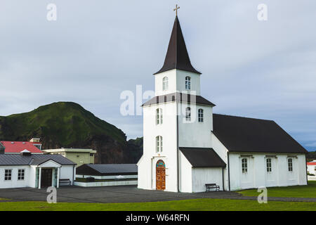 Kirche mit schwarzem Dach, weißen Wänden in traditionellen nordischen minimalistischen Stil auf Vestmannaeyjar Insel Heimaey in Island. Einfache Architektur, Grün Stockfoto