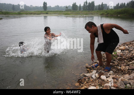 Chinesische Vater Liu Ningliang spielt mit seinen zwei Töchtern in einem Fluss in der Nähe von National Highway, wie er nahm sie für eine 1-monatige Reise auf einem Traktor f Stockfoto