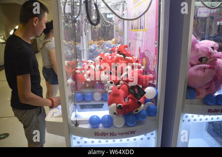 Die Spieler greifen Puppen auf gewöhnliche Puppe - grabbing Maschinen mit einer Shopping Mall in Shanghai, China, 7. August 2018. Ein 2-stöckiges riesigen menschlichen Puppe - ergreifende m Stockfoto