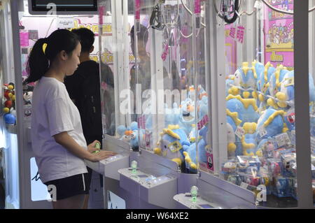 Die Spieler greifen Puppen auf gewöhnliche Puppe - grabbing Maschinen mit einer Shopping Mall in Shanghai, China, 7. August 2018. Ein 2-stöckiges riesigen menschlichen Puppe - ergreifende m Stockfoto