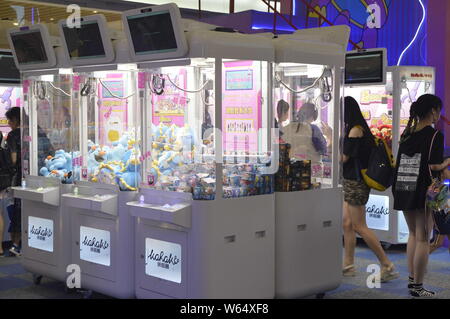 Die Spieler greifen Puppen auf gewöhnliche Puppe - grabbing Maschinen mit einer Shopping Mall in Shanghai, China, 7. August 2018. Ein 2-stöckiges riesigen menschlichen Puppe - ergreifende m Stockfoto