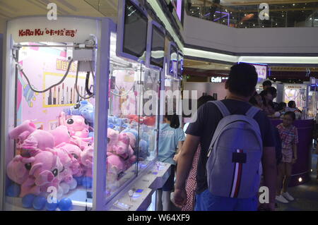 Die Spieler greifen Puppen auf gewöhnliche Puppe - grabbing Maschinen mit einer Shopping Mall in Shanghai, China, 7. August 2018. Ein 2-stöckiges riesigen menschlichen Puppe - ergreifende m Stockfoto